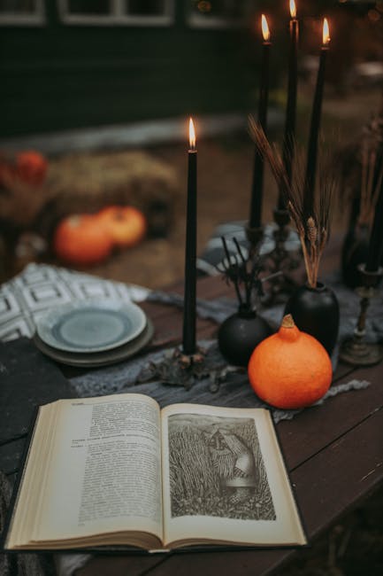 A Halloween-themed setup featuring an open book, black candles, and pumpkins on a rustic table.